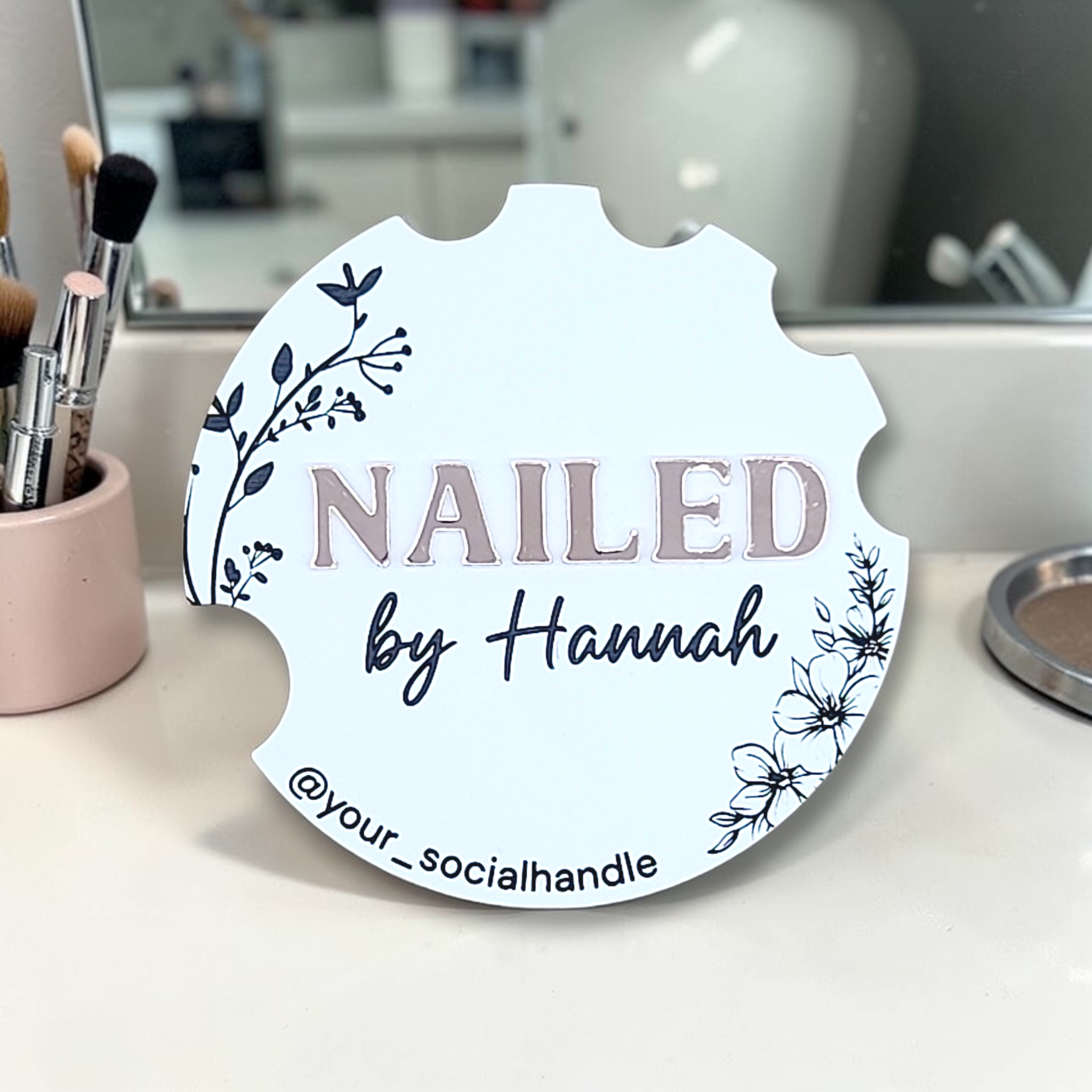 White floral Nailfie Disc with silver NAILED lettering, by Hannah, and a social media handle
